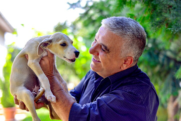 Portrait of a happy man holding a cute mixed breed dog on sunny day