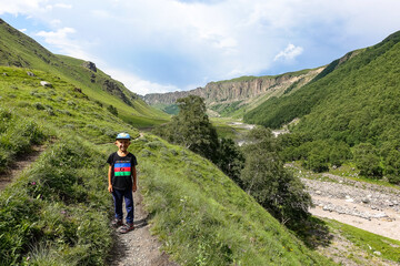 Fototapeta na wymiar Boy at the Kyzyl-Kol River, surrounded by the Caucasus Mountains near Elbrus, Jily-su, Russia