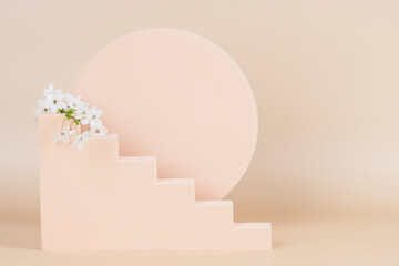 Geometric podium platform stand for product presentation and spring blossoming flowering tree branch with white blossom on pastel beige background. Front view
