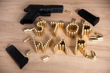 Napis stop war ułożony z naboi na stole, obok leży broń i załadowane magazynki - obrazy, fototapety, plakaty