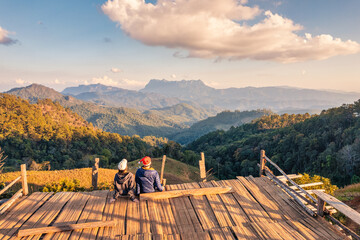 Asian couple enjoying the mountain view on wooden balcony in the evening at countryside
