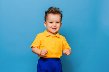 Cute little grimaces stands on a blue background. Funny kid