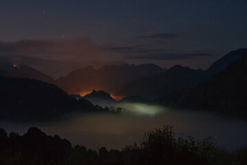 Glowing colorful fog from a village in a hill with beautiful star field in twilight sky a sunset...