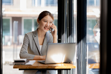 Asian woman talking on the phone, she is a salesperson in a startup company, she is calling...