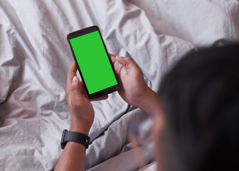 An over the shoulder shot of a mobile phone, man sitting in bed. Chroma key