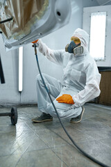 Technician in safety clothing spraying car paint