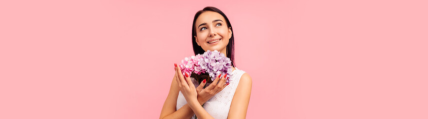 woman with a flower bouquet with peony flowers in her hands. Woman on a pink background, celebrating mother's day