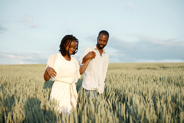 Young black couple walking through green field