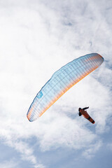 Paragliding flight with a man in a lying position in a nice cloud sky. Extreme and adventure sports. Copy space