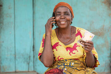 elderly african woman holding some money, making phone call