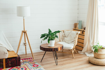 Rattan armchair and floor lamp in living room interior with plants. Cozy interior in boho style....