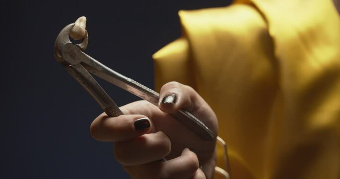 Woman holding pincers that clamp a tooth