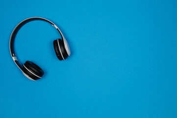 Fototapeta na wymiar White headphones with black earmuffs on a blue background.Top view .Copy space