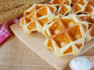 Yummy  waffles on wooden tray with cup of flour near them