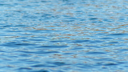 Conceptual cold blue abstract background water. Waves on water, reflection of ripples on the river. Blue water texture.