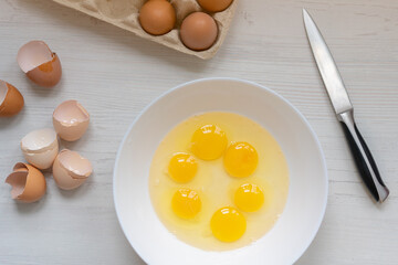 cooking process, eggs in a white bowl on the kitchen table, flat view, breakfast concept