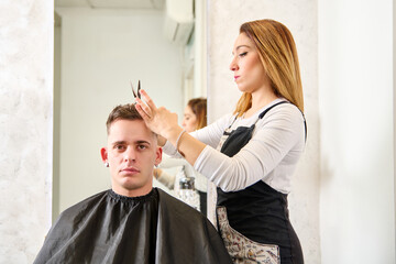 Hairdresser cutting hair and styling a client in the barbershop