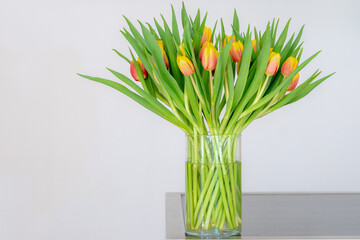 Selective focus of yellow orange tulip bouquet flower in the glass vase, Nature floral background,...