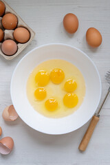 cooking process, eggs in a white bowl on the kitchen table, flat view, breakfast concept