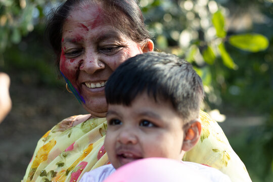 Happy Asian Indian Kid Boy And Grandmother Enjoying The Festival Of Colors With Holi Color Powder Called Gulal Or Rang