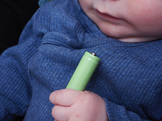  baby holds in his hands and pulls an electric battery into his mouth