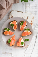 Mini sandwiches with salmon, curd cheese, parsley and rye bread in form of hearts. Valentine's day homemade creative food. Love breakfast design. Selective focus and copy space