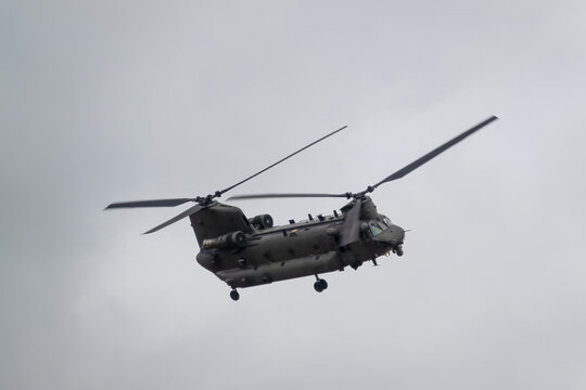 close up of an RAF Chinook tandem-rotor CH-47 helicopter flying fast and low in a cloudy blue grey sky on a military battle exercise, Wilts UK