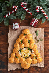 Bread buns Christmas tree with Roasted camembert cheese and rosemary on rustic background. Holiday recipes. Christmas menu. Christmas or Xmas pastries. Top view. Copy Space.