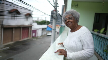 A senior black woman looking out from home balcony looking at neighborhood