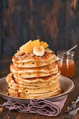 Pancakes. Homemade fluffy pancake with banana, walnut and caramel for breakfast on dark wooden background. Delicious pancakes for traditional American breakfast. Selective focus. Mock up.