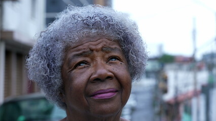 A contemplative senior black woman looking up at sky an African person eyes looks up