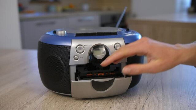 woman pushes eject button on portable radio and takes out retro audio cassette