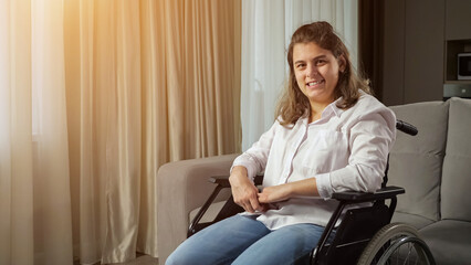 Young disabled woman with infantile cerebral paralysis in white shirt smiles sitting in wheelchair...