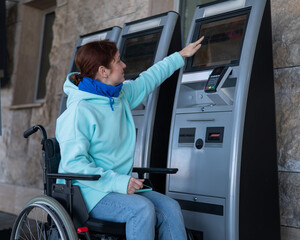 Caucasian woman in a wheelchair buys a train ticket at a self-service checkout. 