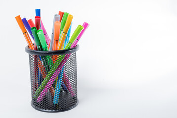 Black pencil holder full of colored pencils isolated on white background with space for text