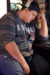 Obraz premium Feeling depressed. A young man looking sad and lonely while sitting at the bar.