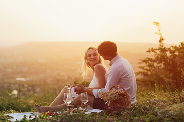 Picnic for lovers. Happy young couple spend time outdoors at sunset of the day. They look each other with love.  