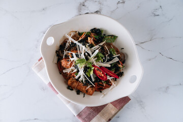 stir-fried Korean Japchae Bowl with chapchae noodles, beef and vegetable isolated on mat top view on grey marble background