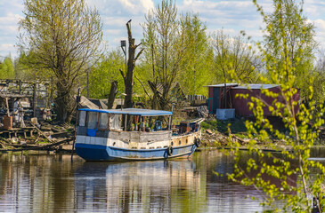 Fototapeta premium Sunny May day on the banks of the Izhora river, boats and boats under repair.