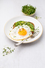 Keto breakfast fried egg, avocado and bread in a white plate. Keto diet concept.
