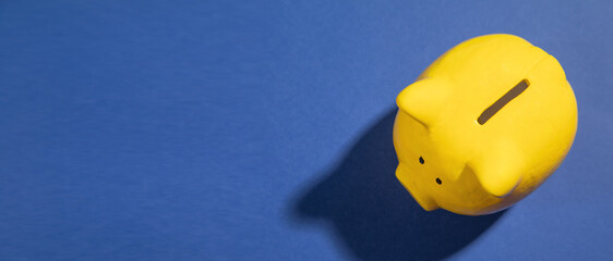 Yellow piggy bank on the blue paper background.