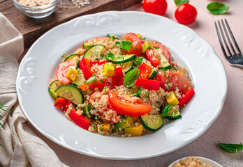 Healthy vegetable salad with quinoa and fresh herbs on a gray background.