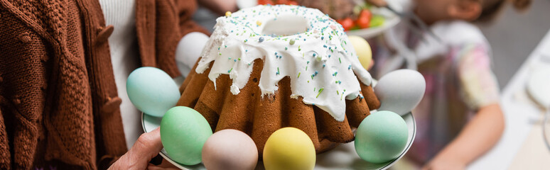 delicious easter cake and painted eggs near cropped family, banner.