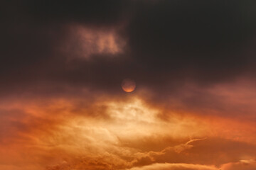 layer of black clouds covering the sun during twilight, with golden clouds floating on the horizon.
