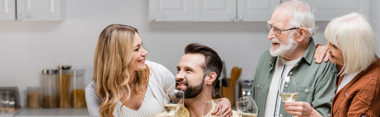 joyful family holding wine glasses while celebrating easter at home, banner.