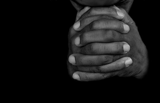 praying to god with hands together with dark background stock photo