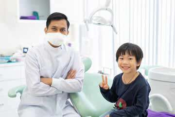 The Asian boy feel happy to sit on the dental chair with dentist in dental clinic