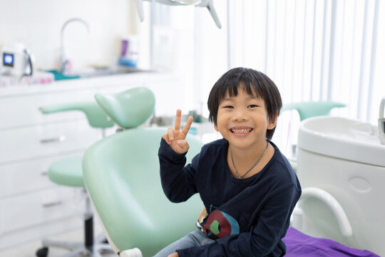 The Asian boy feel happy to sit on the dental chair in dental clinic