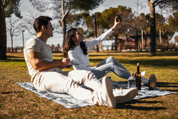 couple in picnic, she is taking a selfie to remember the moment in the future