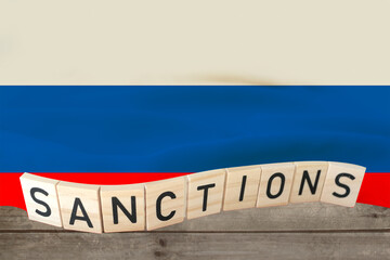word sanctions on wooden letters against the background of national flag of Russia, concept of...
